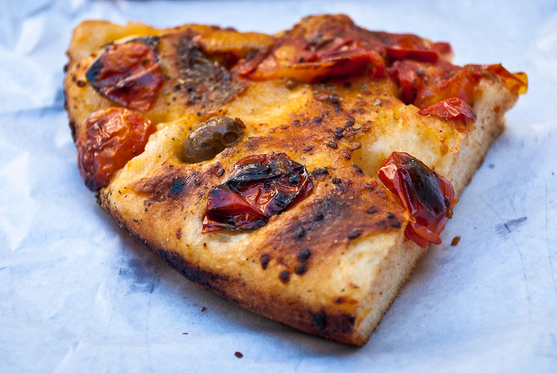 Bari-style vegetarian focaccia with tomatoes on a sheet of white paper.