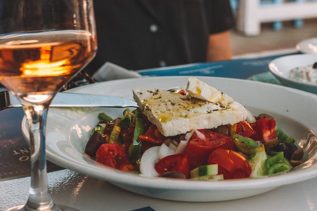 A plate of Greek salad with a glass of wine on the table of a restaurant in Budapest.