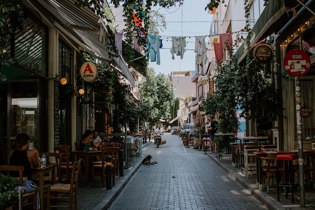 Bustling downtown Athens street lined with inviting restaurants, offering alfresco dining with outdoor tables and chairs.