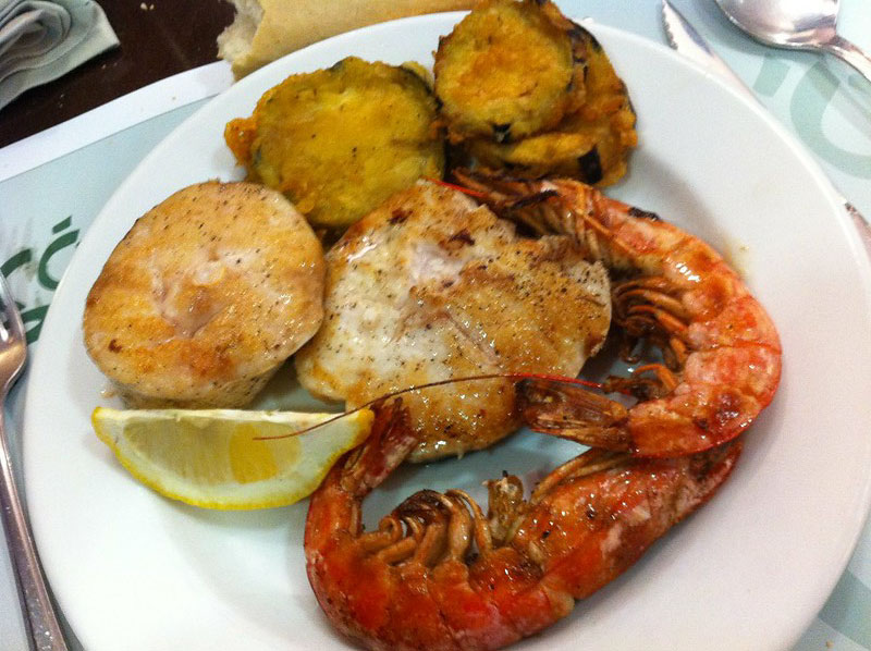 Fried fish dish with shrimp and a wedge of lemon at El Racò restaurant in Barcelona.
