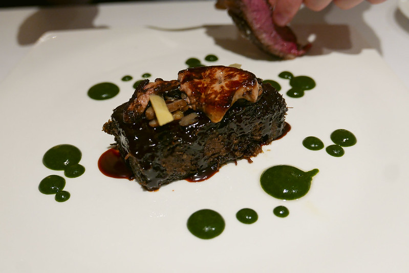 Plate with a cut of meat topped with a dark glazed sauce and drops of a reduced basil sauce at the Michelin-starred Xerta restaurant from the Michelin Guide.